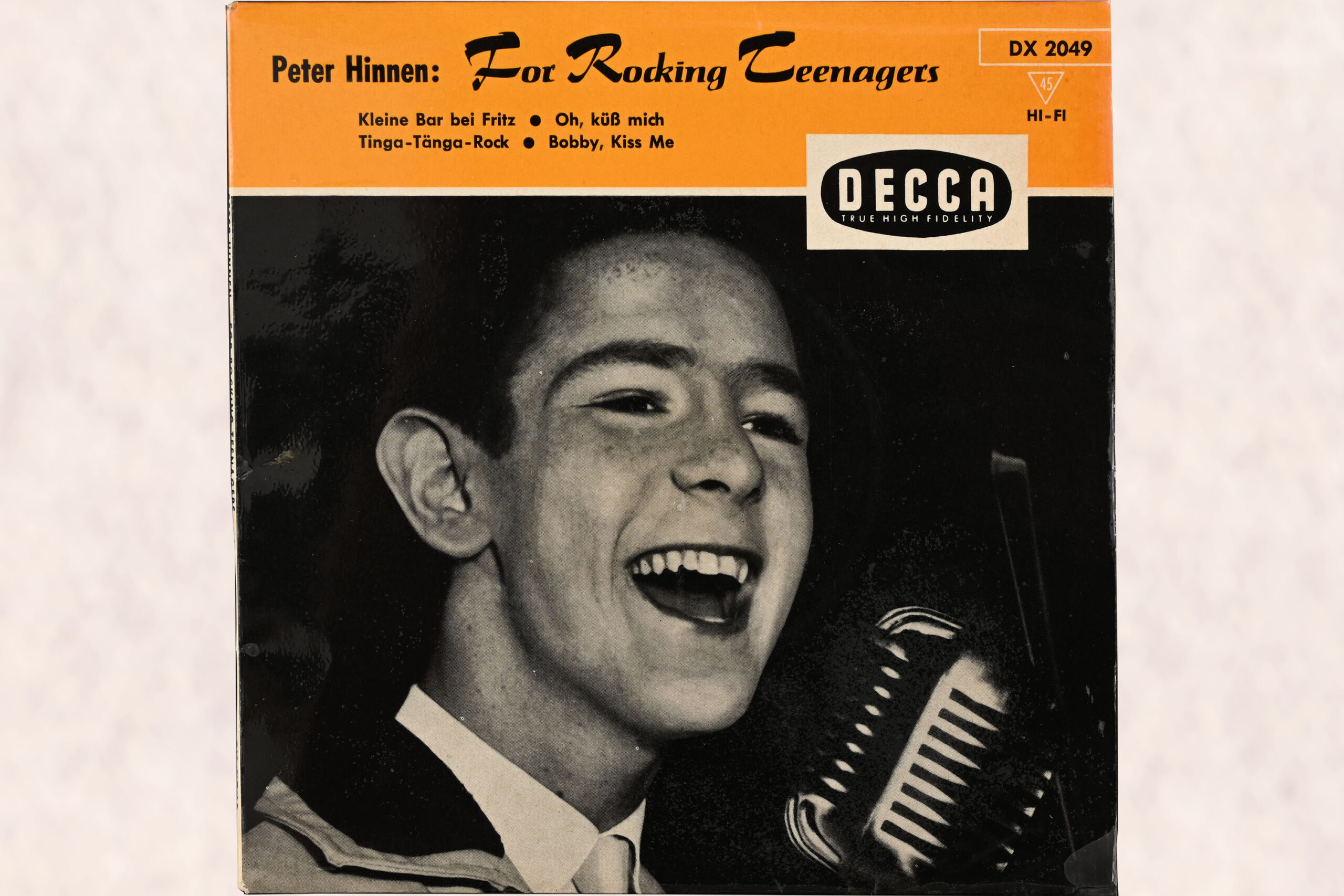 Cover einer Schallplattenhülle, auf dem ein schwarz-weiss Foto von Peter Hinnen zu sehen ist, der in ein Mikrofon singt; auf einem orangen Balken am oberen Rand steht der Titel der EP "For Rocking Teenagers" und ist ein grosses Logo der Plattenfirma Decca angebracht.